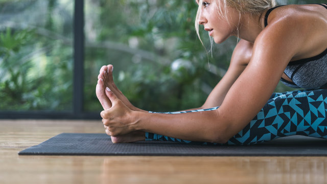 Young adult athletic girl doing yoga in sport centre