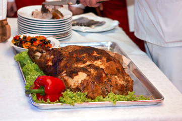 The meat is cooked in the oven. A big piece of meat. Chef cuts the finished meat in the kitchen. Meat with vegetables.
