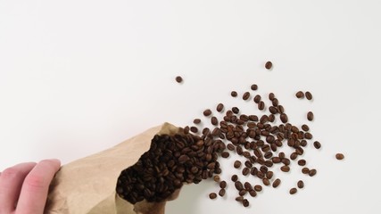 Pour coffee beans on the table from the bag. Close up.