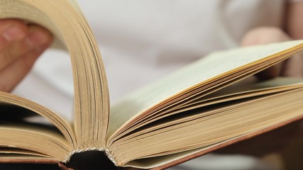 Man flipping pages in book for browsing. Close up.