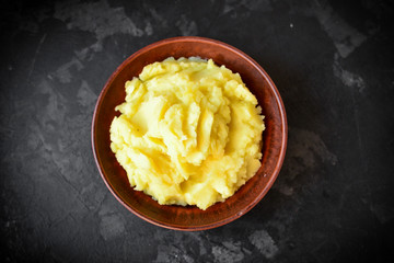 Mashed potatoes in a bowl. Dark background, top view, place for text.