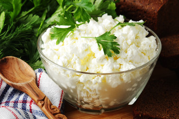 A bowl with cottage cheese, a bunch of green and rye bread