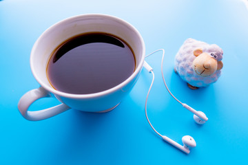 Headphones and coffee cup on blue desk table. Music concept. Top view with copy space