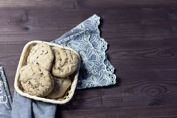 Bread buns with sesame seeds in basket, table cloth  on brown wooden background