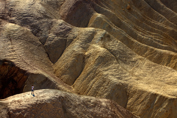 California / USA - August 22, 2015: A tourist walking in landscape and rock formations near Zabriskie point near Death Valley National Park, California, USA