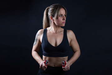 Obraz premium Fitness athlete woman with black clothes and red grips, black background, sports