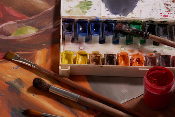 Master at work drawing made with gouache paints, still life. Paint cans and brushes hand of the master.