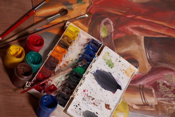 Master at work drawing made with gouache paints, still life. Paint cans and brushes hand of the...