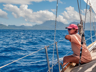 young woman on a sailing yacht,approaching Raiatea Island from sea, French Polynesia, Society...