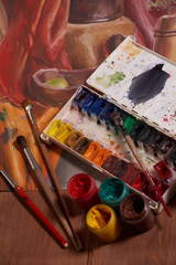Master at work drawing made with gouache paints, still life. Paint cans and brushes hand of the master.