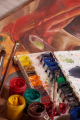 Master at work drawing made with gouache paints, still life. Paint cans and brushes hand of the master.