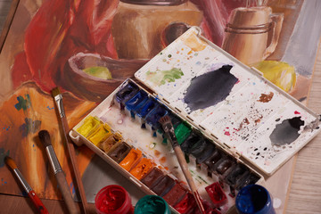 Master at work drawing made with gouache paints, still life. Paint cans and brushes hand of the...