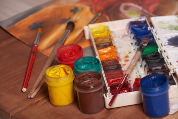 Master at work drawing made with gouache paints, still life. Paint cans and brushes hand of the...