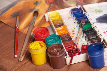 Master at work drawing made with gouache paints, still life. Paint cans and brushes hand of the master.