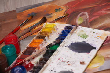 Obraz premium Master at work drawing made with gouache paints, still life. Paint cans and brushes hand of the master.