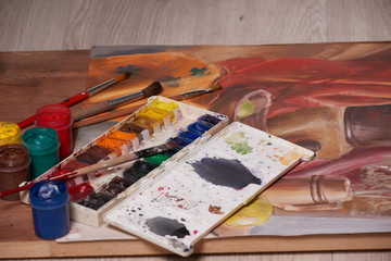 Master at work drawing made with gouache paints, still life. Paint cans and brushes hand of the master.