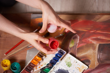 Master at work drawing made with gouache paints, still life. Paint cans and brushes hand of the...