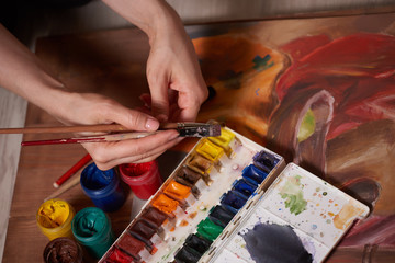 Master at work drawing made with gouache paints, still life. Paint cans and brushes hand of the master.