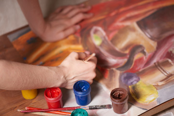 Master at work drawing made with gouache paints, still life. Paint cans and brushes hand of the...