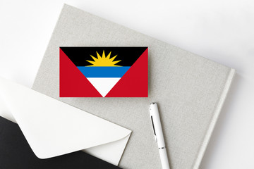 Antigua and Barbuda flag on minimalist letter background. National invitation envelope with white pen and notebook. Communication concept.