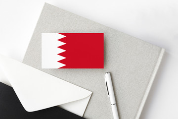 Bahrain flag on minimalist letter background. National invitation envelope with white pen and notebook. Communication concept.