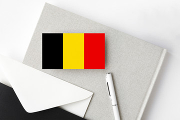 Belgium flag on minimalist letter background. National invitation envelope with white pen and notebook. Communication concept.