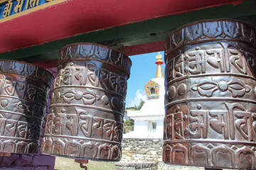 Tengboche Monastery (or Thyangboche Monastery), also known as Dawa Choling Gompa. View of blurred tibetan buddhist stupa through prayer wheels with mantras. - obrazy, fototapety, plakaty