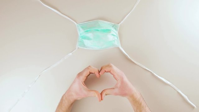 Coronavirus fine della pandemia, successo con simbolo del cuore da parte di un medico con mascherina. Virus definitivamente debellato.