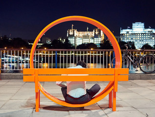 man sitting on orange design bench