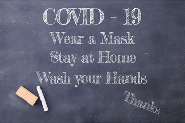 Covid-19 wear a mask, Stay at Home and wash your hands chalkboard inscription.