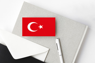 Turkey flag on minimalist letter background. National invitation envelope with white pen and notebook. Communication concept.