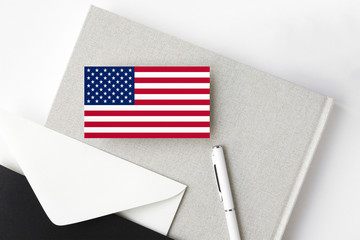 United States flag on minimalist letter background. National invitation envelope with white pen and notebook. Communication concept.
