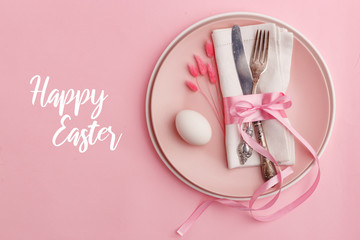 Elegant stylish table setting. Knife and fork on a napkin on a plate on a pink background.