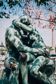 Tourist attraction "The Kiss" statue by Rodin in Tuileries Gardens and Place de la Concorde in Paris, France with Luxor Egyptian obelisk in background