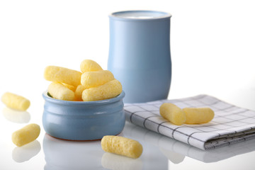 Sweet, corn sticks in a blue plate with a jug of milk, in bright colors. Delicious, airy treat.
