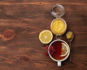 Fototapeta na wymiar honey, hot lemon tea and rowanberry on a wooden backround. Vitamin tea for illness prevention.