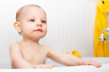Portrait of concentrated baby boy bathing in bathtub