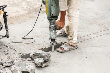 Construction worker using jackhammer drilling concrete surface