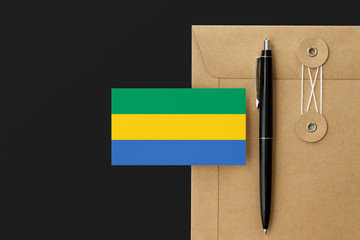 Gabon flag on craft envelope letter and black pen background. National invitation concept....
