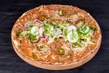 Pizza with beef mince, vegetables and cheese baked in the oven, served with salad and fresh vegetables