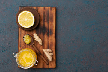 Ginger, lemon and honey in a wooden spoon on dark background . Flat lay, top view, copy space.