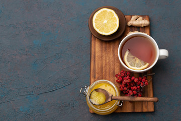 Fototapeta na wymiar Lemon honey and ginger on wooden plate with a cup of hot tea background. Top view, mockup, flat lay. Season illness prevention. Background with copy space and design mockup.