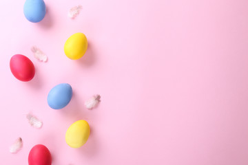 Bunch of blank painted Easter eggs of different bright colors on pink paper texured background with a lot of copy space for text. Top view, flat lay, close up.