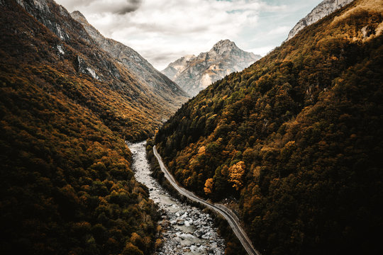 Strasse am Fluss in der Schweiz umgeben von Bergen mit herbstlichen B&auml;umen