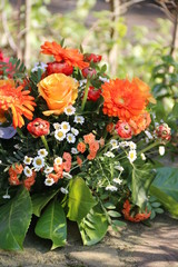 Blumen der Trauer in Orange auf dem Friedhof nach Beerdigung