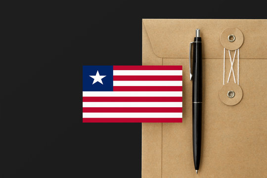 Liberia flag on craft envelope letter and black pen background. National invitation concept. Invitation for education theme.