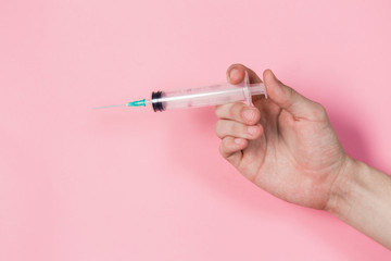 Syringe in a hand on a pink background