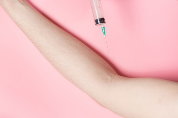 Syringe in a hand on a pink background