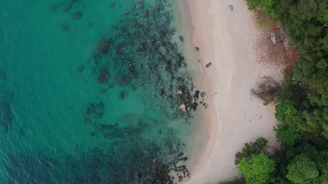Top aerial drone view of tropical empty beach with turquoise sea water and rocks