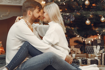 Lady in a white sweater. Family sitting on a floor. Couple near christmas tree.